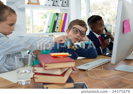 Kids as business executives discussing over desktop pc Kids as business executives discussing over desktop pc 34375879