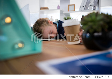 Boy as business executive sleeping while holding coffee cup 34375993