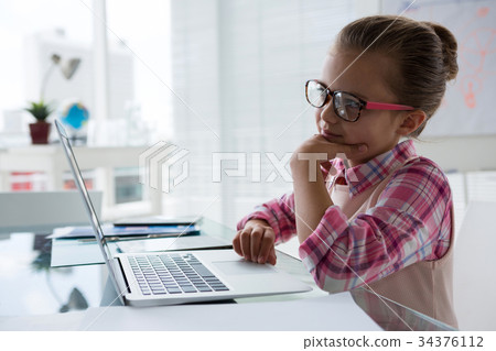 Girl as business executive using laptop while sitting Girl as business executive using laptop while sitting 34376112