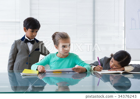Businessman looking at businesswomen working in boardroom 34376243