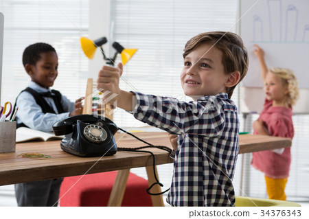 Businessman gesturing at table while colleagues working in background in office 34376343