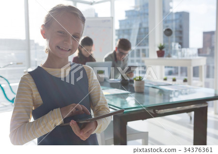 Portrait of businesswoman using tablet while colleagues discussing in background 34376361