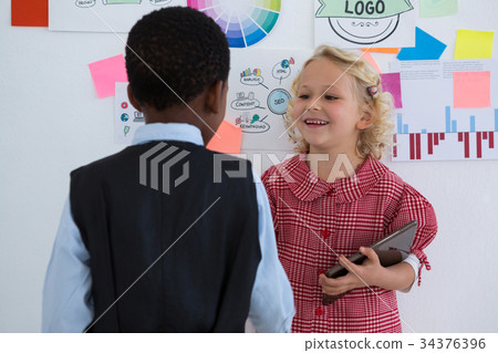 Business people discussing while standing by whiteboard in office Business people discussing while standing by whiteboard in office 34376396