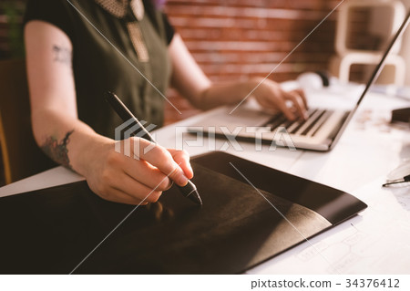 Executive working on stylus while using laptop in office 34376412