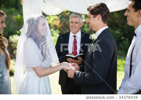 Minister giving speech to bride and groom Minister giving speech to bride and groom 34376439