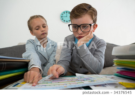 Colleagues discussing documents while sitting on sofa Colleagues discussing documents while sitting on sofa 34376545
