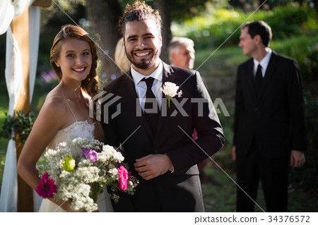 Happy bride and groom standing in park 34376572