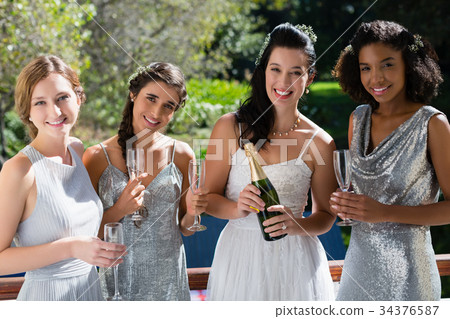 Bride and bridesmaids having champagne Bride and bridesmaids having champagne 34376587