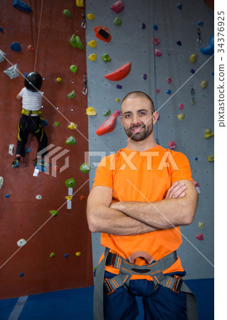 Trainer standing with arms crossed in fitness studio Trainer standing with arms crossed in fitness studio 34376925