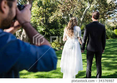 Photographer taking photo of newly married couple Photographer taking photo of newly married couple 34376987