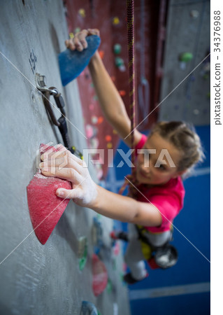 Determined teenage girl practicing rock climbing 34376988