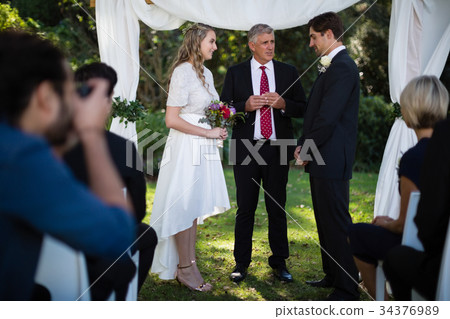 Minister giving speech to bride and groom Minister giving speech to bride and groom 34376989
