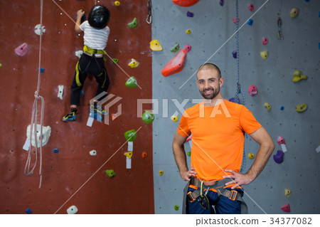 Trainer standing with hands on hip in fitness studio 34377082
