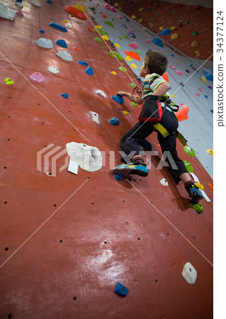 Boy practicing rock climbing in fitness studio Boy practicing rock climbing in fitness studio 34377124