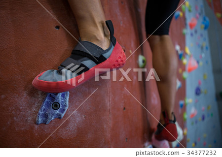 Woman practicing rock climbing in fitness studio Woman practicing rock climbing in fitness studio 34377232