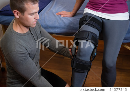 Physiotherapist examining his patients knee 34377243