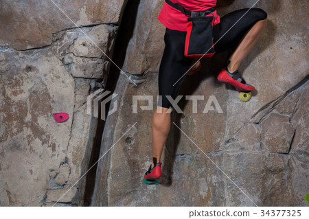Low section of woman practicing rock climbing Low section of woman practicing rock climbing 34377325