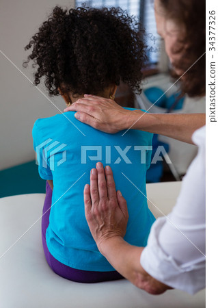 Physiotherapist giving back massage to girl patient Physiotherapist giving back massage to girl patient 34377326