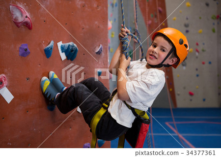 Portrait of determined boy practicing rock climbing Portrait of determined boy practicing rock climbing 34377361