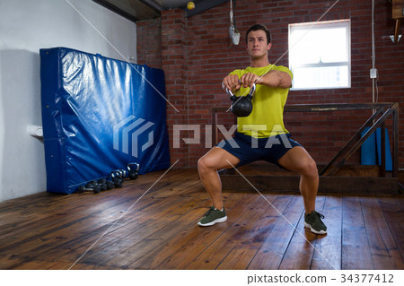 Determined man exercising with kettlebell 34377412