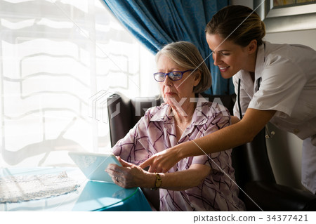 Female doctor assisting woman in using digital tablet 34377421