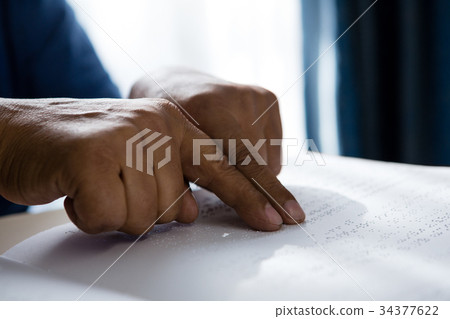 Cropped hands on senior man reading braille book in retirement home 34377622