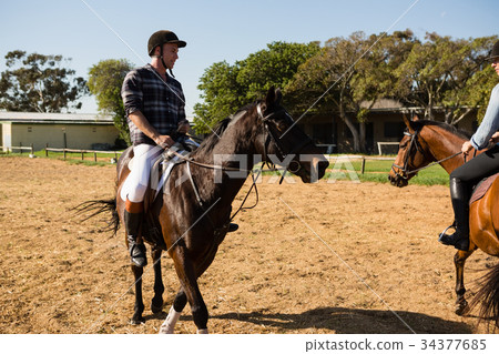 Two male friends riding horse in the ranch Two male friends riding horse in the ranch 34377685