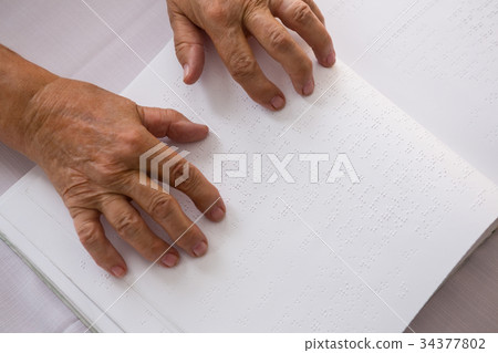 Cropped hands of senior woman reading braille in nursing home 34377802