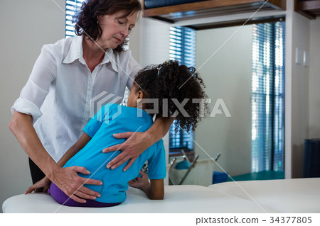 Physiotherapist giving back massage to girl patient Physiotherapist giving back massage to girl patient 34377805