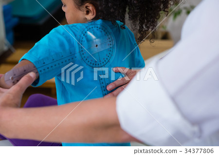 Physiotherapist examining girl patients back with goniometer 34377806
