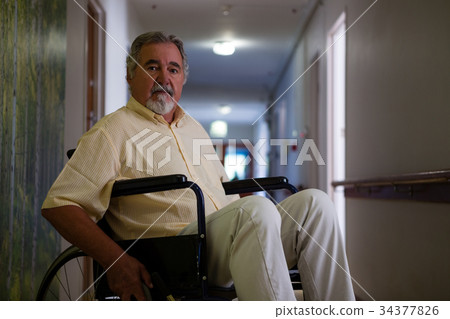 Portrait of senior man sitting on wheelchair in corridor Portrait of senior man sitting on wheelchair in corridor 34377826
