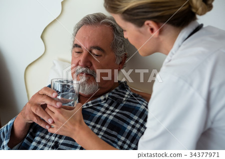 Side view of female doctor giving water to senior patient Side view of female doctor giving water to senior patient 34377971