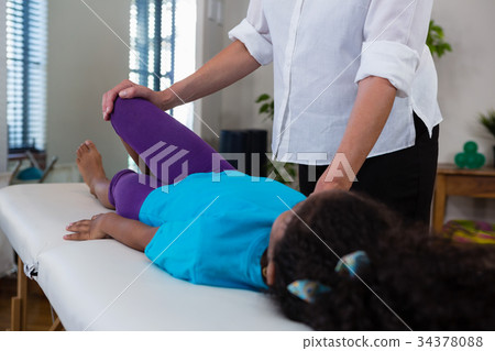 Physiotherapist giving leg massage to a girl patient 34378088