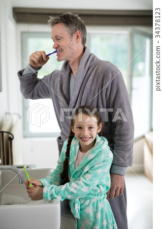 Father and daughter brushing teeth in bathroom 34378123