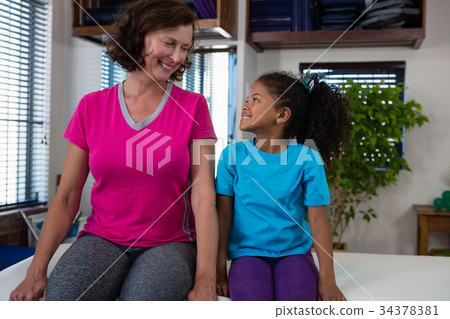 Girl and physiotherapist interacting on bed 34378381