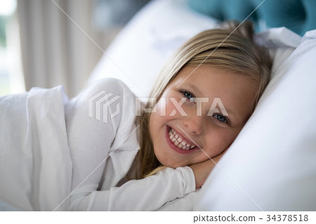 Smiling girl lying on bed in bedroom 34378518