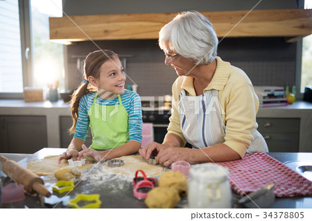 Grandmother and granddaughter cutting dough with a cookie cutter 34378805