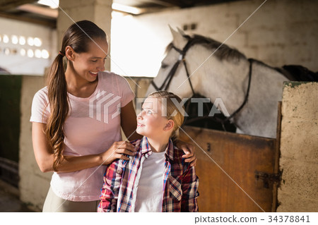 Sisters talking while standing against horse Sisters talking while standing against horse 34378841