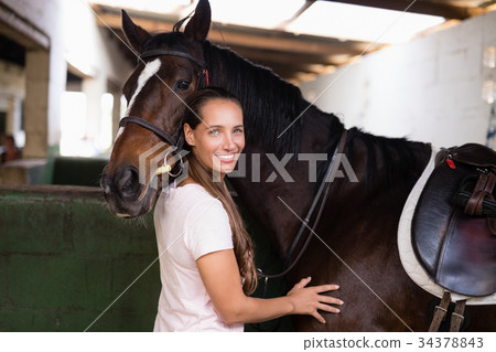 Portrait of smiling female jockey standing by horse 34378843