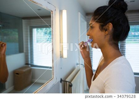 Woman brushing teeth at home Woman brushing teeth at home 34379128