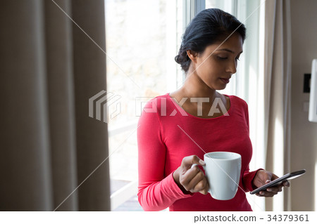 Young woman with coffee cup using phone 34379361