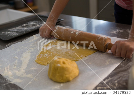 Cropped hands of boy rolling dough 34379523