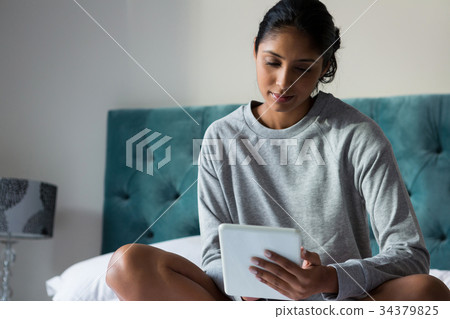 Relaxed woman using digital tablet on bed Relaxed woman using digital tablet on bed 34379825