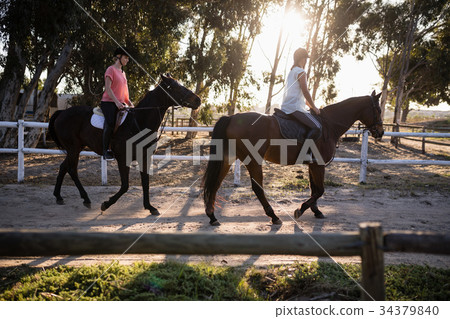 Friends riding horses at barn Friends riding horses at barn 34379840