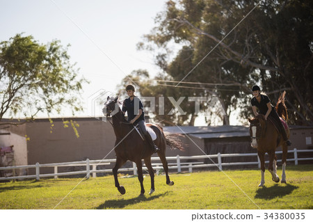 Friends riding horse at equestrian center 34380035