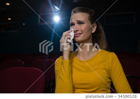 Woman crying while watching movie Woman crying while watching movie 34380128