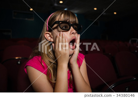Surprised girl wearing 3D glasses while watching movie Surprised girl wearing 3D glasses while watching movie 34380146