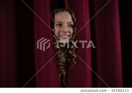 Female artist peeking through the red curtain 34380213