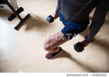 Low section of male athlete exercising lunges in fitness club 34380369