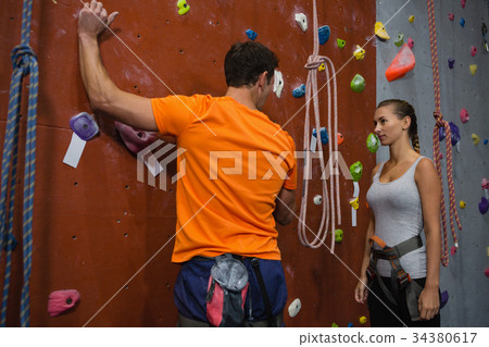 Athletes discussing while standing by climbing wall Athletes discussing while standing by climbing wall 34380617
